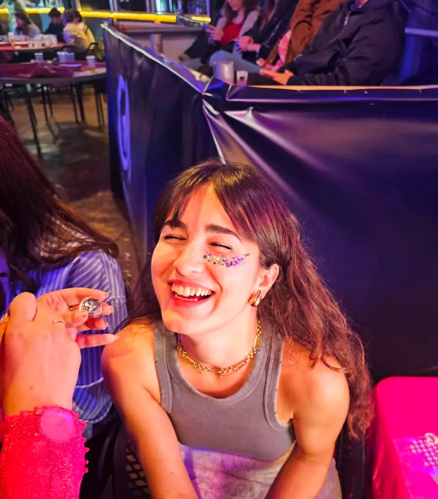 Chica sonriendo con toque de glitter en mejilla izquierda