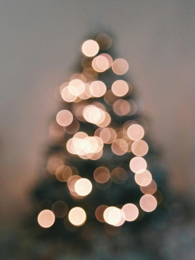Soft focus of a Christmas tree showcasing warm bokeh light circles, creating a festive and cozy atmosphere.